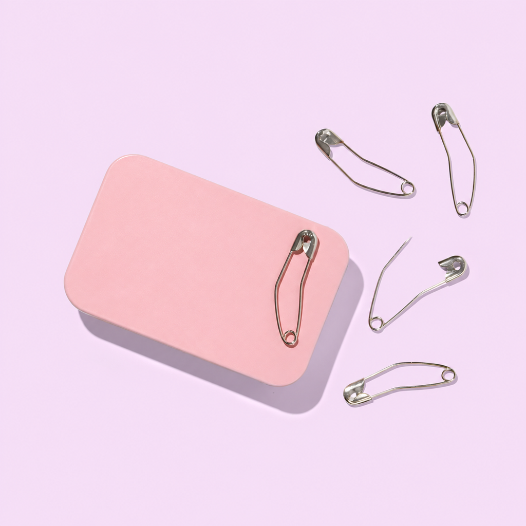 Curved basting pins in a storage tin, product detail view